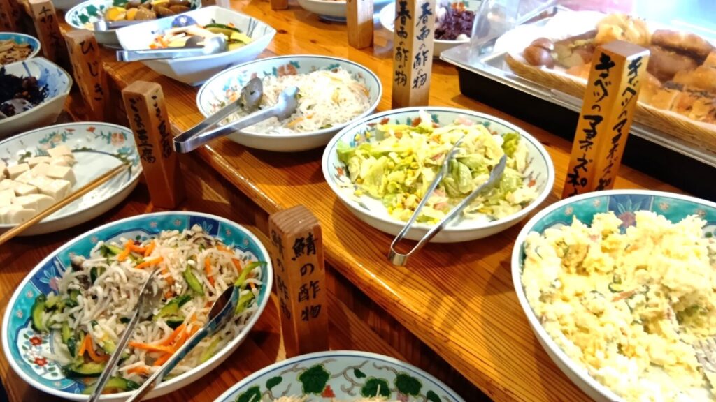 ヘルシーな料理が並ぶ。鮭の酢の物や、ポテサラ、キャベツマヨ、ごま豆腐はかなり減ってる。